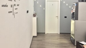 A hallway with a white door labeled "1" and a reception desk to the left. The walls have various words and phrases in different fonts and orientations. - Chroma Italy - Chroma Deka (Rome)