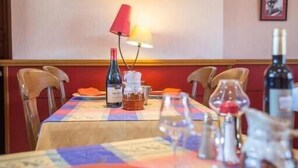 Una mesa de comedor con mantel, botellas de vino, copas y un cuadro en la pared.