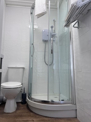 A modern bathroom with a glass-enclosed shower, a toilet, and a bidet. - The Crown Hotel (Corwen)