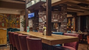 A bar area with a wooden table, red chairs, a brick wall, and a television. - Lord Bagenal Inn (Leighlinbridge)