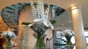 A modern interior with a glass staircase, white flowers in vases, and a large column. - Lord Bagenal Inn (Leighlinbridge)