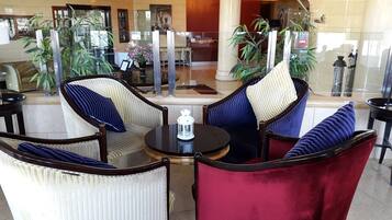 A lobby with a seating area featuring striped chairs and a round table with a lantern.