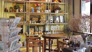 A cozy bookstore with wooden shelves filled with books and decorative items, a round wooden table, and chairs. - Karnvela Phuket (Phuket)