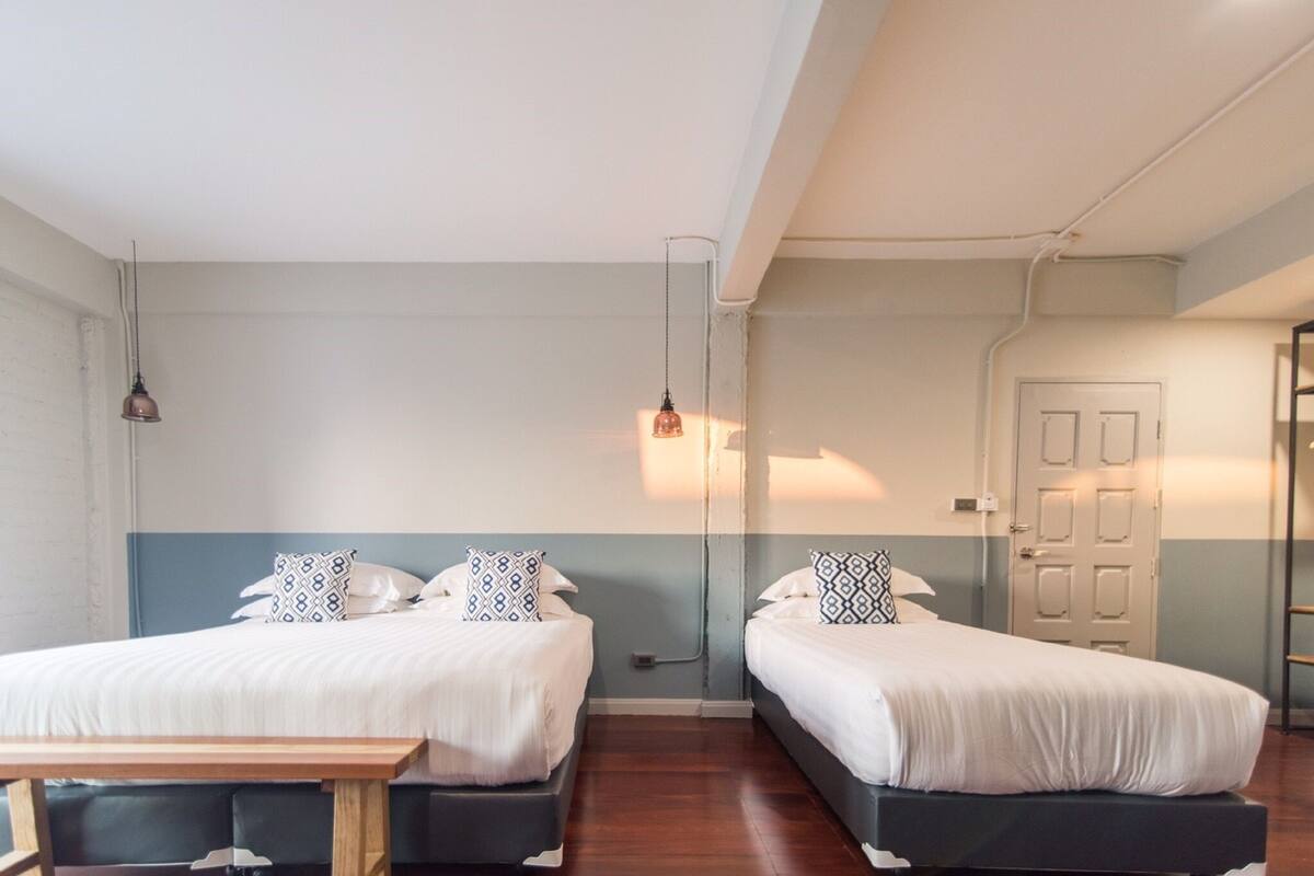 A room with two beds, a wooden table, and a door.