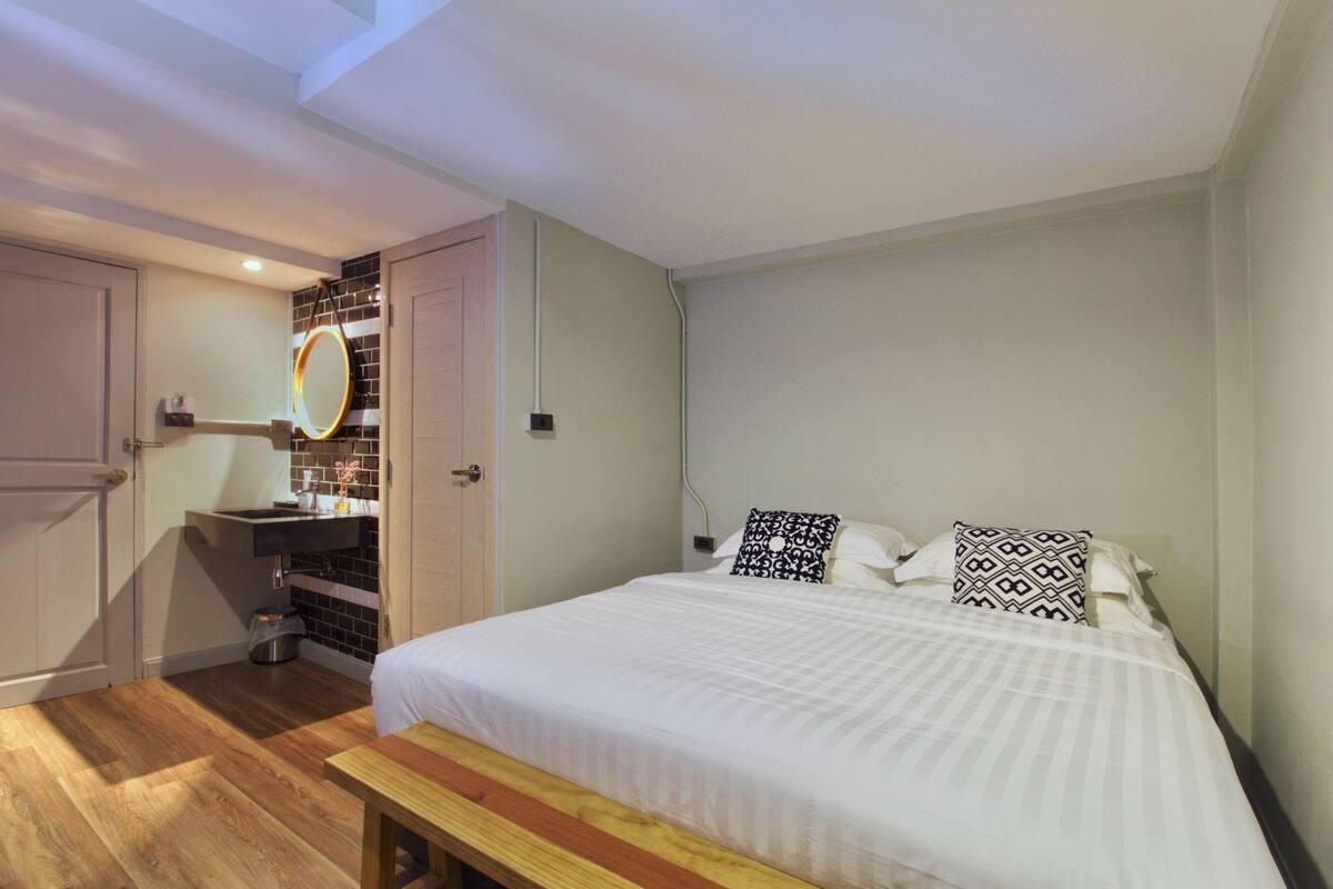 A bedroom with a bed, bedside table, and a bench.