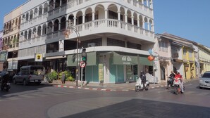 A multi-story building with a curved facade, balconies, and a ground-level storefront. - Karnvela Phuket (Phuket)