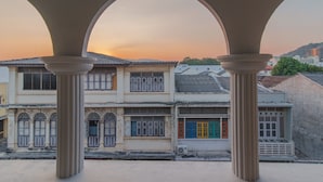 A traditional building with a courtyard, featuring arched structures and a view of the sunset. - Karnvela Phuket (Phuket)