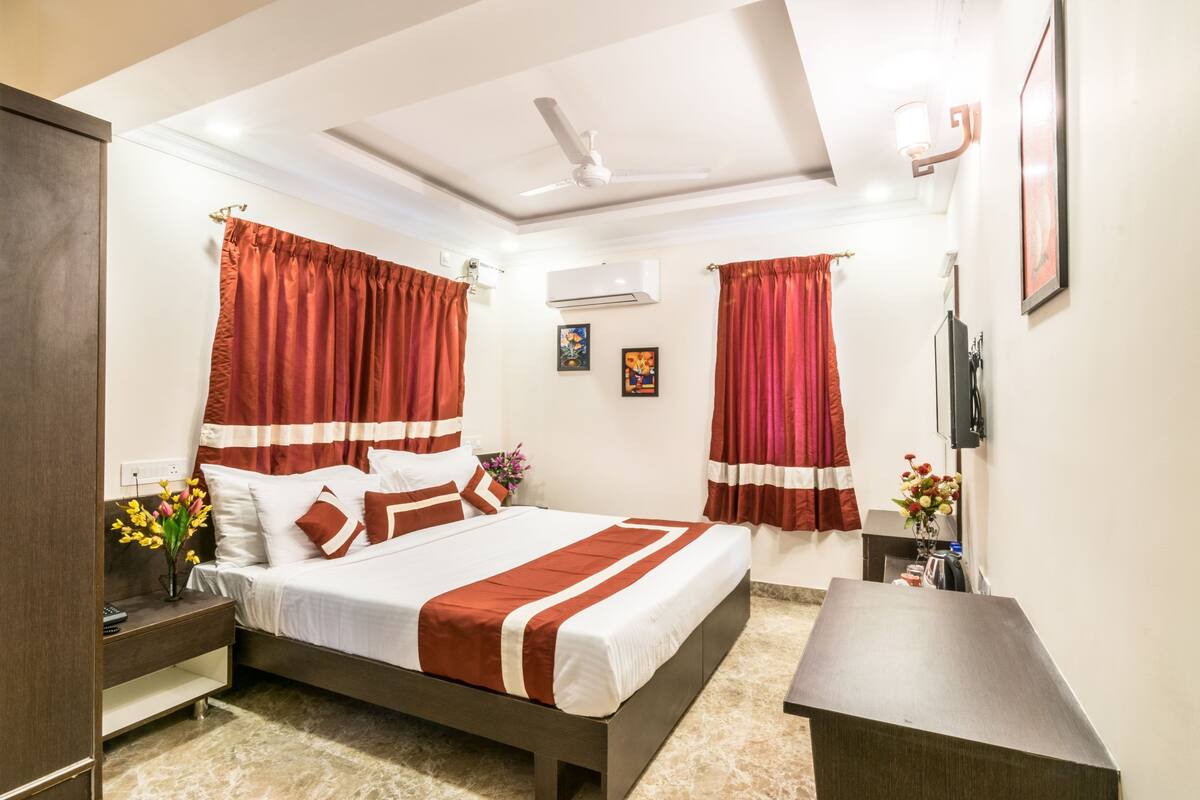 Une chambre d’hôtel équipée d’un lit, de tables de chevet, d’un bureau et d’un ventilateur de plafond.
