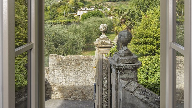 Ventana abierta con vistas a un paisaje montañoso, balaustrada de piedra y pared de piedra.