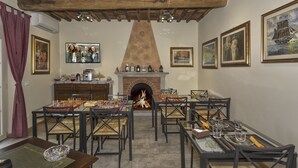 Un comedor con varias mesas y sillas, una chimenea y obras de arte enmarcadas en las paredes.