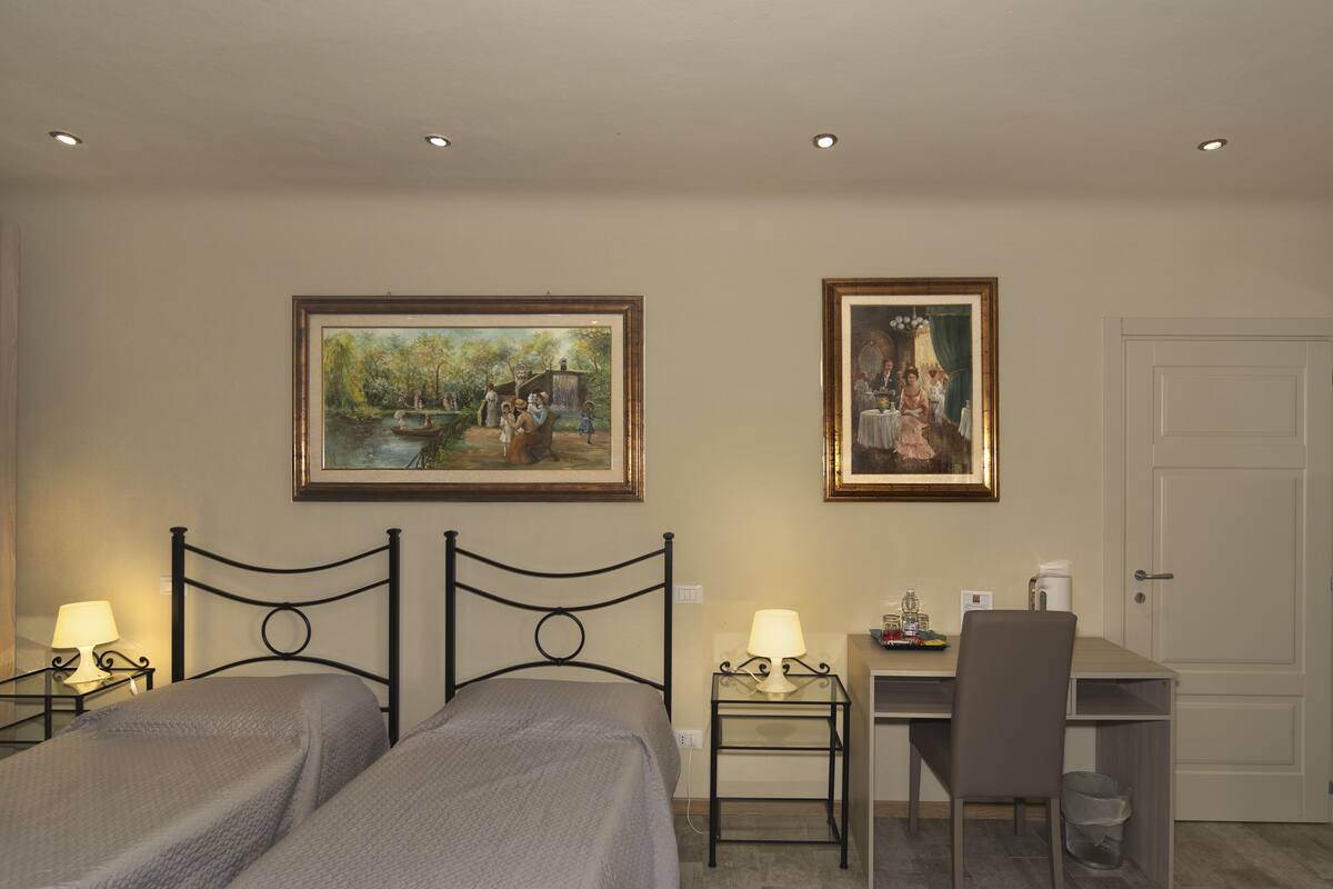 Ein Hotelzimmer mit zwei Betten, einem Schreibtisch und zwei Bildern an der Wand.