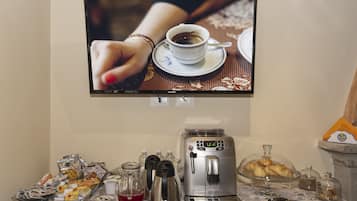 Een koffiehoek met een koffiezetapparaat, kopjes en gebak.