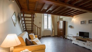 A living room with a wooden ceiling, a sofa, a lamp, a television, and a cabinet. - Charming Suite Cavour Heart of Florence (Florence)