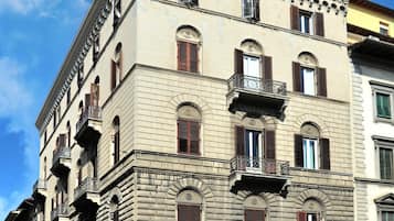 Ein historisches Gebäude mit mehreren Stockwerken, das Bogenfenster und Balkone zeigt.