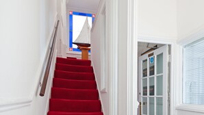 Una escalera con alfombra roja que conduce a una puerta con paneles de vidrio esmerilado.