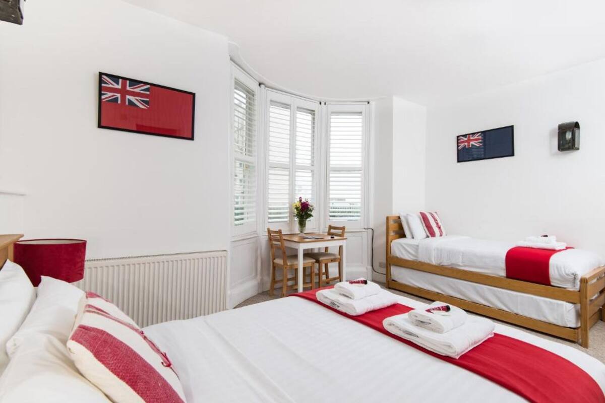 A hotel room with two single beds, a dining table, and two flags on the walls.