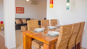 A dining area with a wooden table set for four, surrounded by wicker chairs. - Antonio Sousa Beach 3 Bedroom Apartment (Sal)