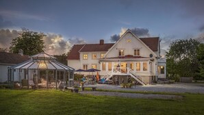 A large, white wooden house with a red-tiled roof, a glass conservatory, and a covered outdoor seating area with umbrellas. - Villa Bro (Brastad)