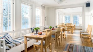 A bright, open dining area with wooden furniture and large windows. - Villa Bro (Brastad)