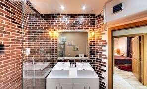 A bathroom with a brick wall, a large mirror, and two sinks. - Cherry Tree Cottage (Varna)