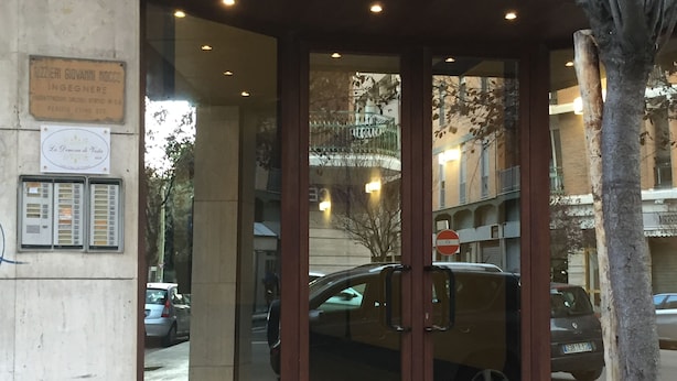 A hotel entrance with a glass door, a signboard, and a tree in the foreground. - La Dimora di Vesta (Lecce)