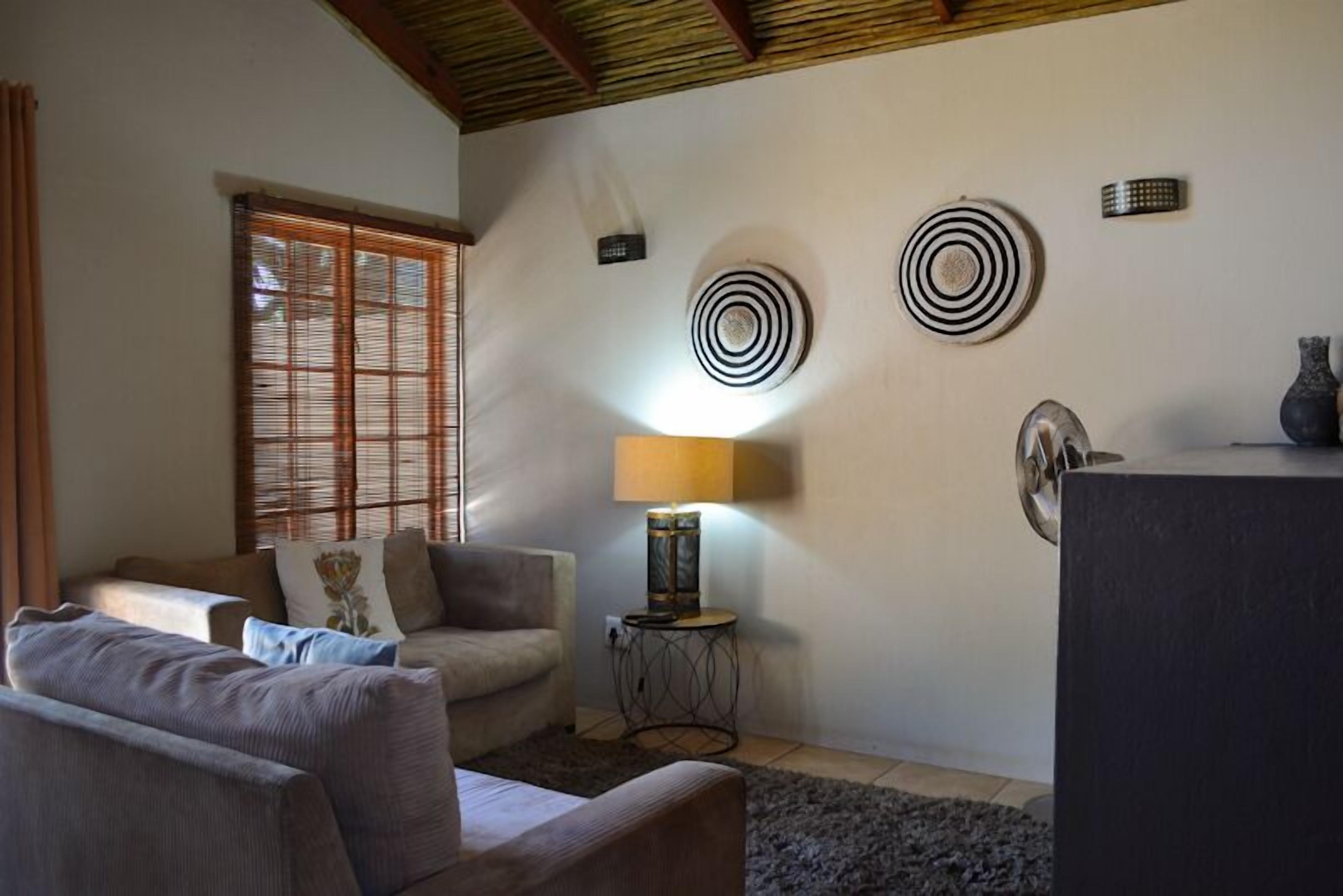 Un salon avec un canapé, une lampe et des œuvres d’art décoratives au mur.