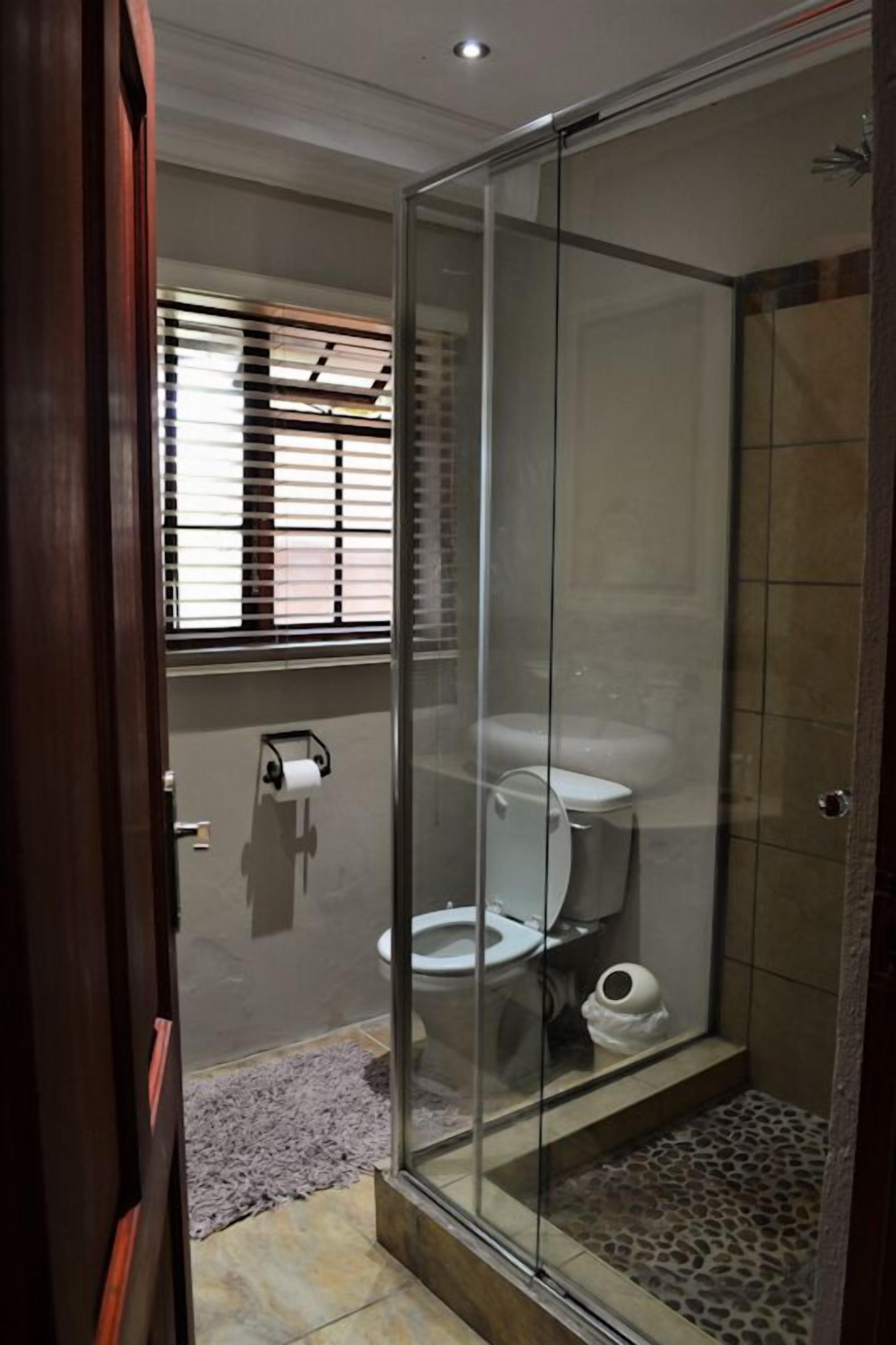 A glass-enclosed shower stall with a toilet and a towel rack visible through the glass.
