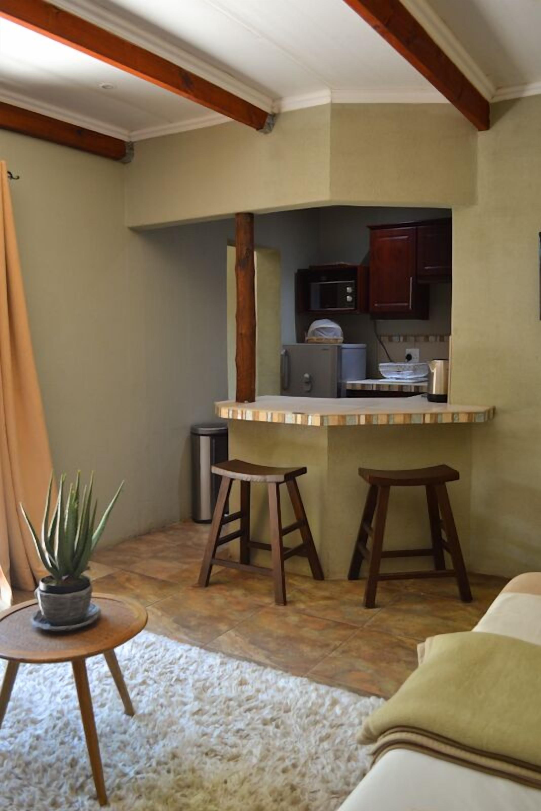 A compact kitchen with a small island, wooden stools, and basic appliances.