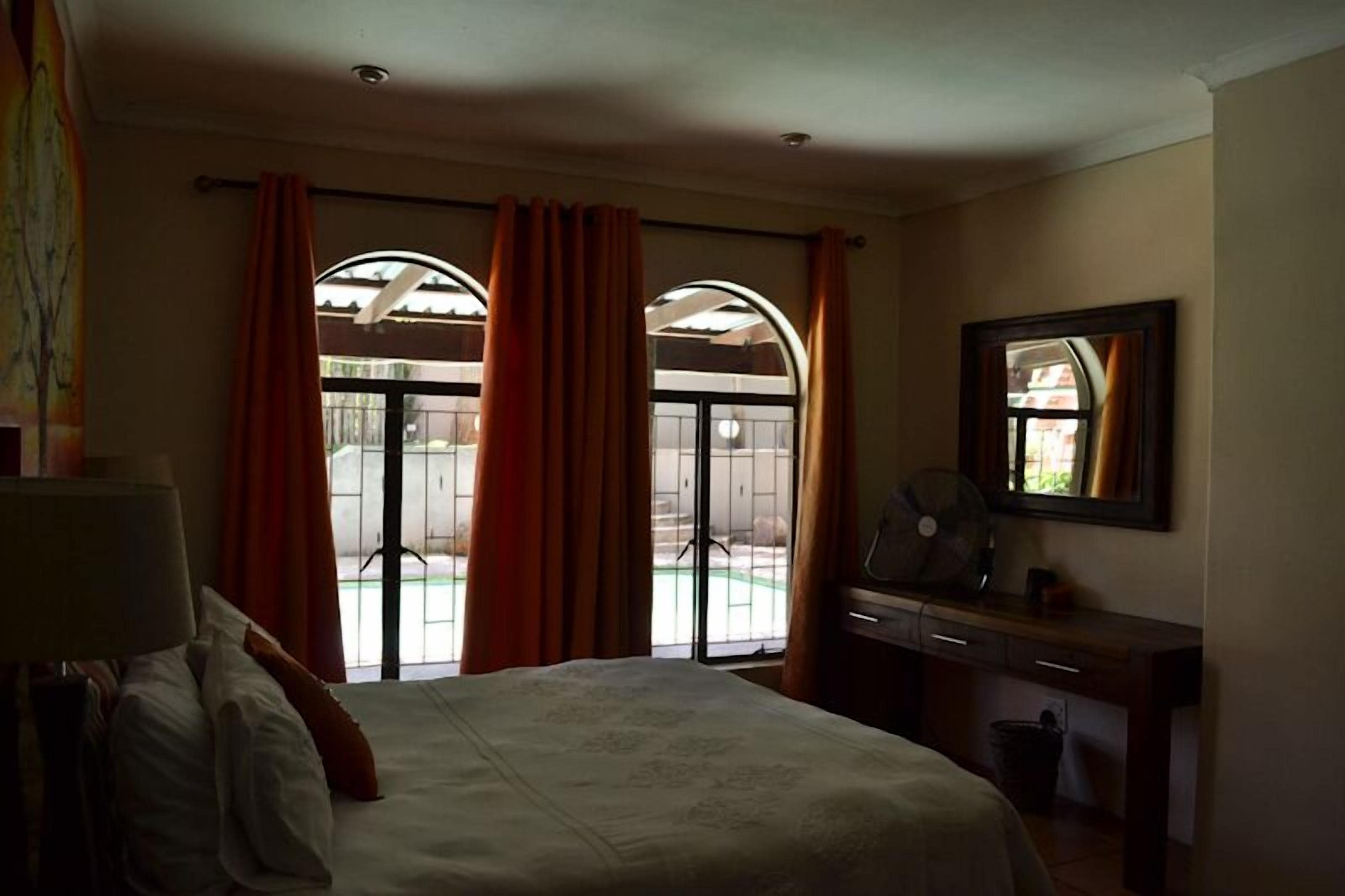 A hotel room with a bed, a desk, a chair, and a window with curtains.