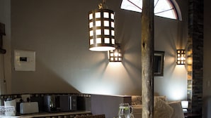 Een gezellige keuken met een ronde tafel, rieten stoelen en een stenen muur.