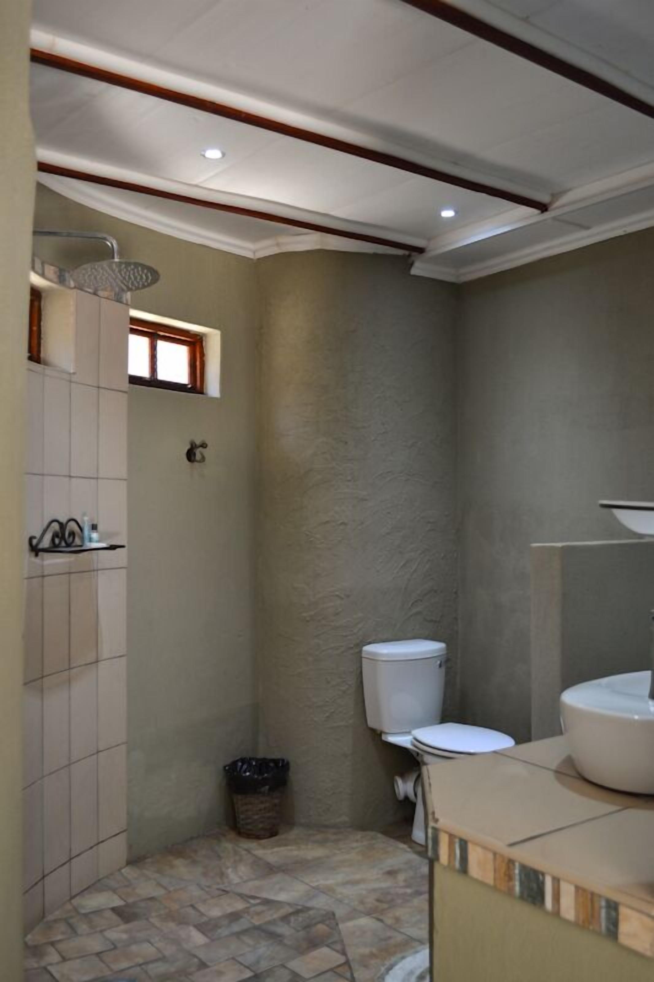 Casa de banho com chuveiro, sanita e lavatório.
