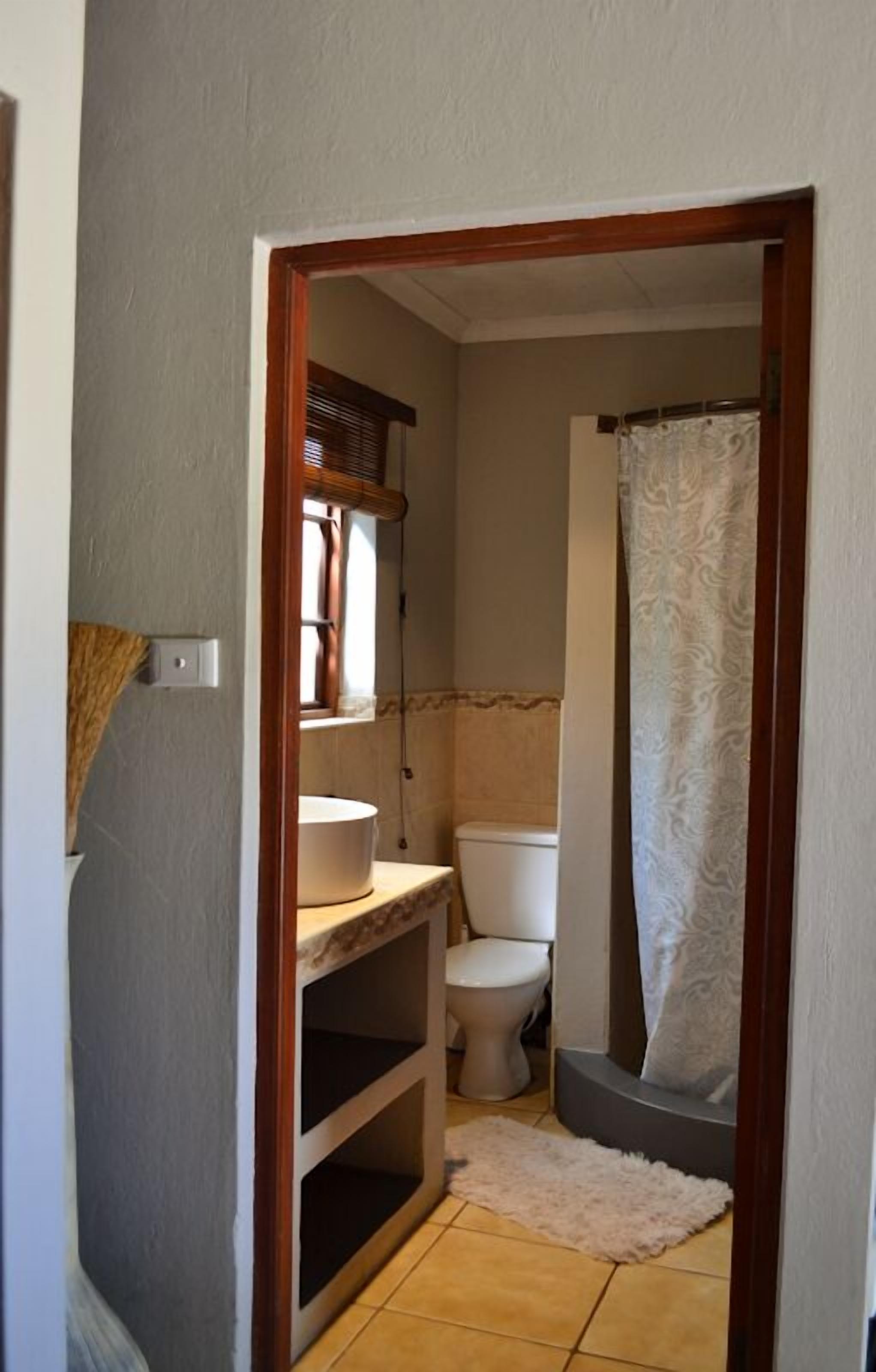 Un baño pequeño con inodoro, lavamanos y ducha.