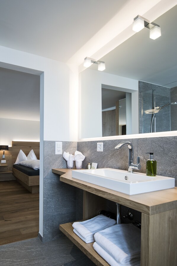 Un baño moderno con un espejo grande, un lavamanos blanco y un mueble de tocador de madera.