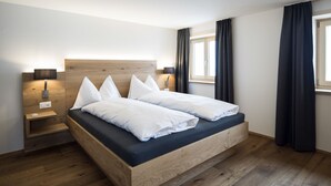 Un dormitorio moderno con estructura de cama de madera, una mesita de noche y una lámpara de pared.