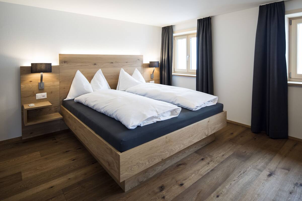 Un dormitorio moderno con estructura de cama de madera, una mesita de noche y una lámpara de pared.