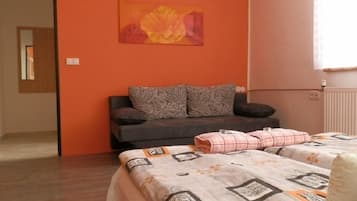A bedroom with a sofa bed, a patterned bedspread, and a floral painting on the wall.