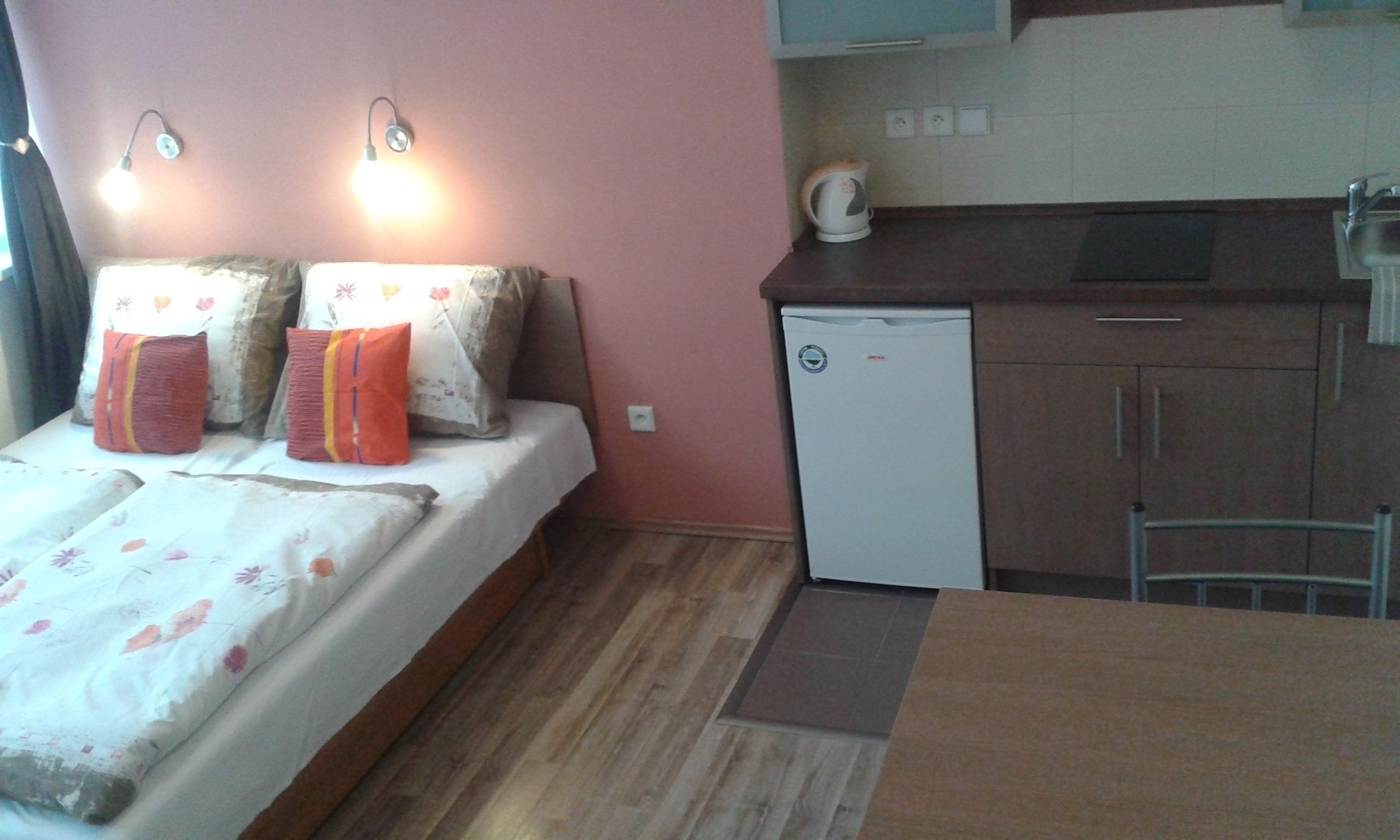 A compact room with a bed, a small kitchenette, and a dining area.
