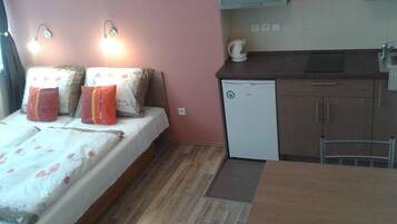 A compact room with a bed, a small kitchenette, and a dining area.