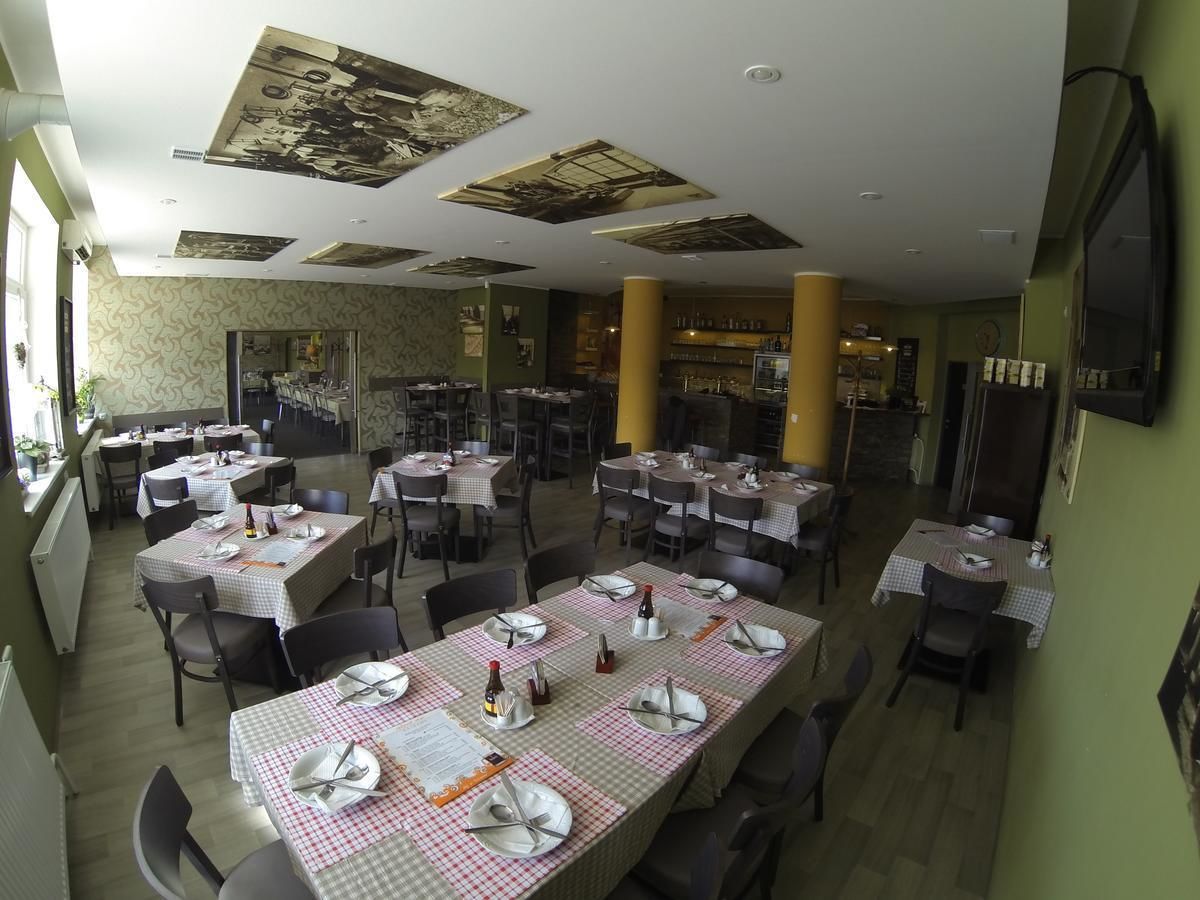 A restaurant with multiple tables set for dining, featuring checkered tablecloths and neatly arranged cutlery.