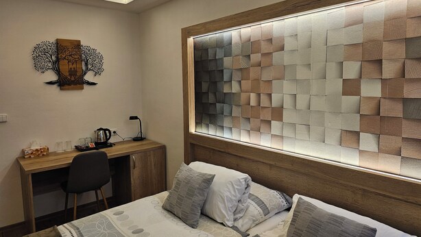 A bedroom with a bed, a desk, and a wall art piece. - Hotel Gól Prostějov (Prostejov)