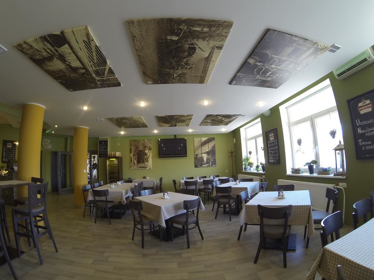 Un restaurante con varias mesas y sillas, una pared verde y decoración en el techo.