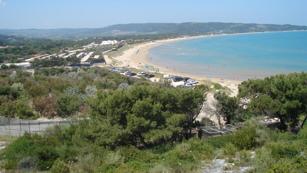 A coastal view with a beach, parked cars, and buildings in the background. - Residence Giardino (Vieste)