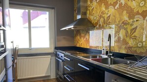 A modern kitchen with stainless steel appliances, a window with a view, and a decorative floral wall. - Siesta Rooms (Karlskrona)