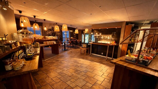 A restaurant with a tiled floor, wooden furniture, and hanging lights. - Karlskrona H&H (Karlskrona)