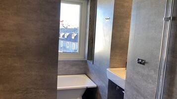 A bathroom with a bathtub, a window, and a sink.