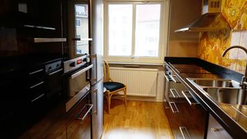 Una cocina compacta con horno integrado, una silla, una ventana y un lavamanos de acero inoxidable.