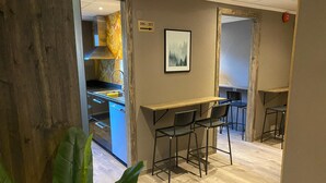 A modern kitchen with stainless steel appliances, a wooden table with chairs, and a framed picture on the wall. - Karlskrona H&H (Karlskrona)