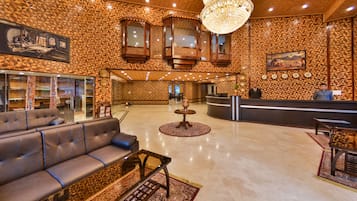 A lobby with a reception desk, a sofa, a chandelier, and patterned walls.