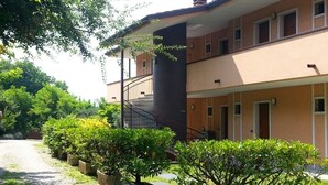 A two-story building with a paved driveway and potted plants. - Hotel Castello S. Antonio (Lazise)