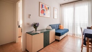 A modern living room with a sofa, a small table, and a cabinet. There are two framed artworks on the wall.